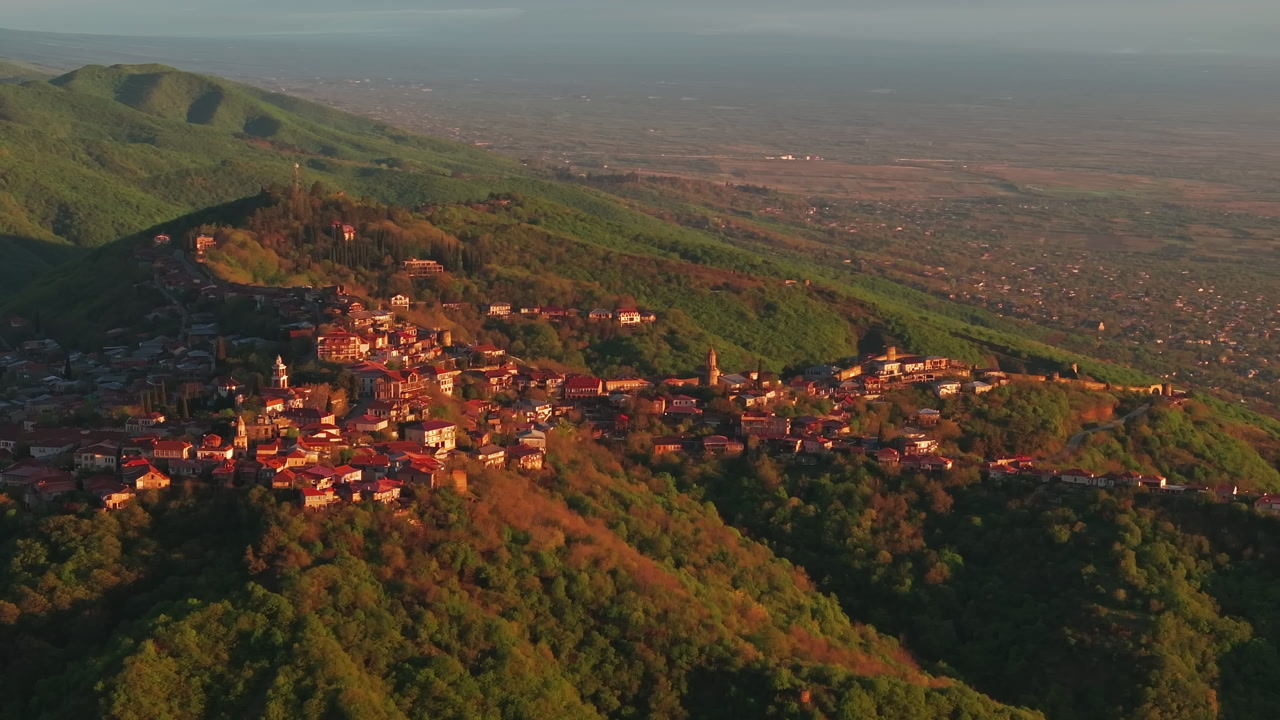 Drone aerial of Sighnaghi, Georgia at sunrise, revealing the town’s historic architecture, elevated setting, and peaceful landscape in warm morning light.