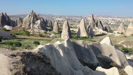 epic revealing cinematic aerial drone shot of a man standing on a hill looking at the fair chimneys in cappadocia, turkey