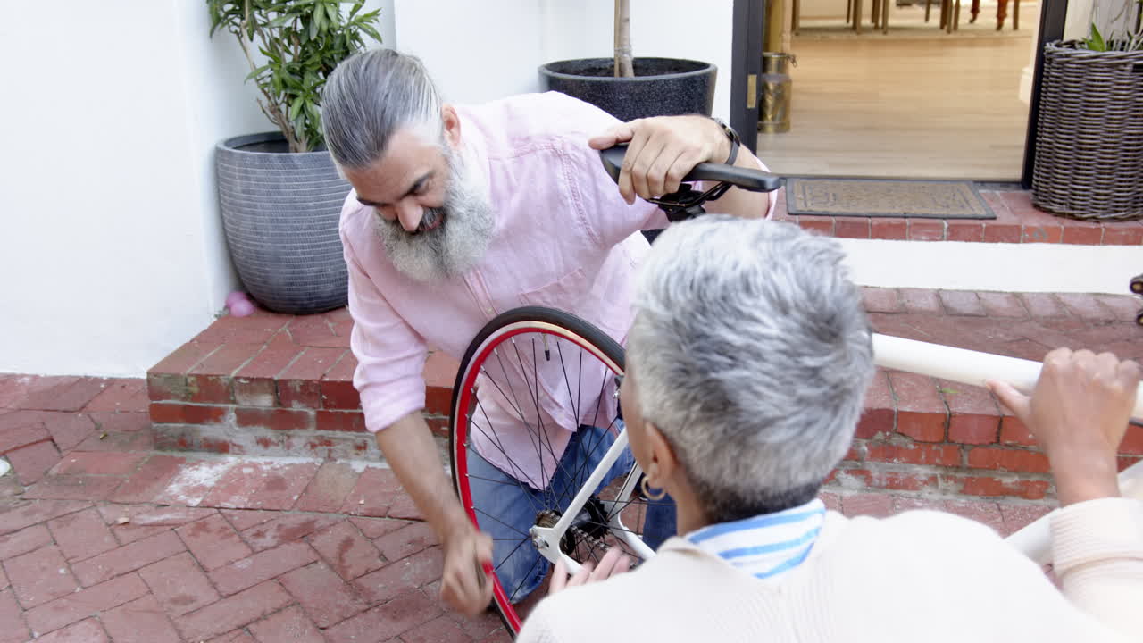 Repairing bicycle wheel, senior couple working together outdoors