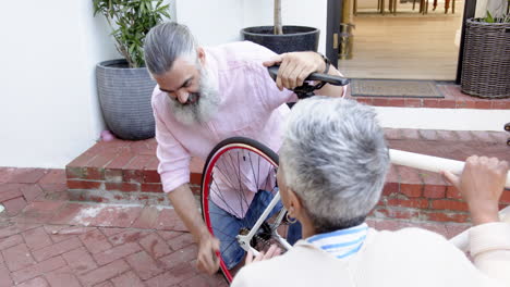 repairing bicycle wheel, senior couple working together outdoors