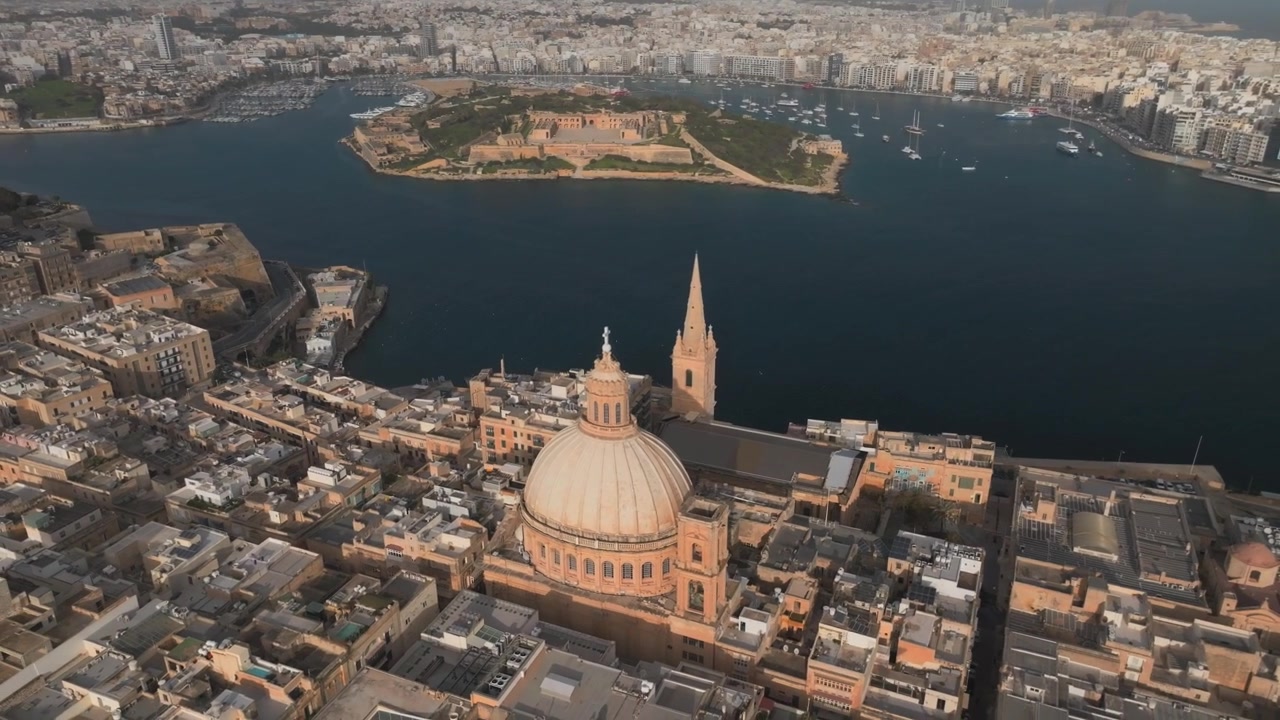 Veduta aerea della città di La Valletta, Malta, con tetti storici, cupola di chiesa, quartieri sul lungomare e il Grand Harbour con un ampio skyline costiero sotto una luce diurna soffusa
