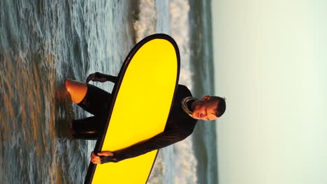 guy in wetsuit with yellow surfboard is returning from surfing the waves