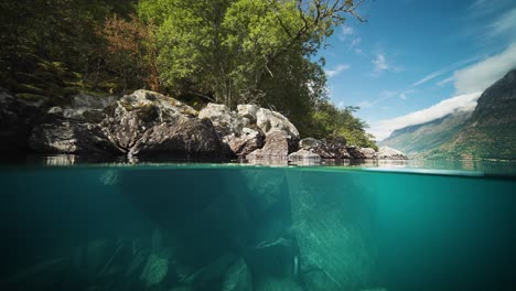 Slow-motion-shot-of-an-rocky-underwater-through-clear-water-of-Loen-Lake-in-Vestland,-Norway-at-daytime