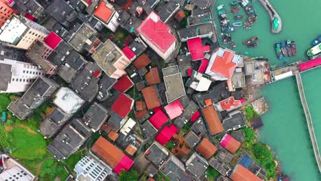 aerial view of gaobei island in putian city, fujian province, china, showcasing a densely built residential area with vibrant rooftops near a bustling harbor filled with fishing boats.