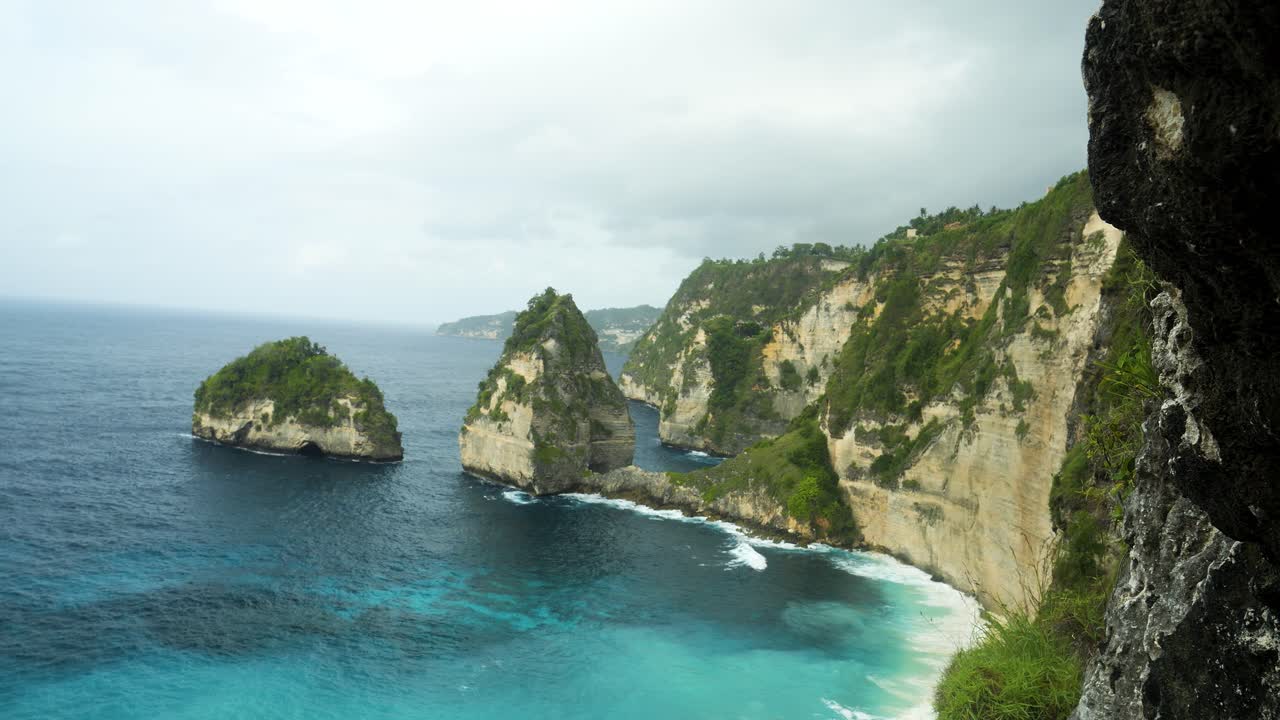 Slow motion panorama shot of the beautiful cliffs in front of diamond beach on nusa penida overlooking the blue sea on a beautiful morning