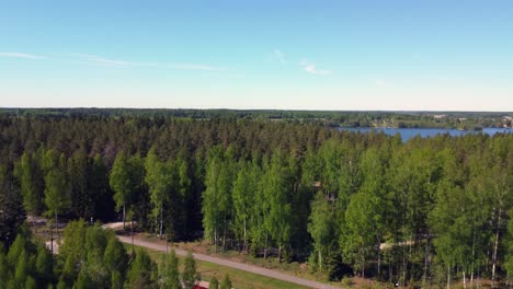 Flyover-vibrant-green-boreal-forest,-revealing-rural-highway-traffic