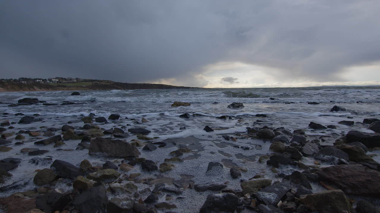 Waves lapping on a beach at high tide on the coast at the start of a storm in the east coast of Scotland in February 2024 Low angle on the rocks Angle 6
