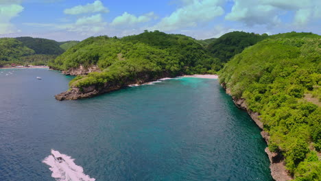 Motorboat-cruising-past-narrow-tropical-sea-bay-with-beach-paradise