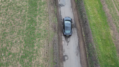 Vehicles-slowly-driving-over-large-potholes-UK-country-road-overhead-birds-eye-view-drone-aerial