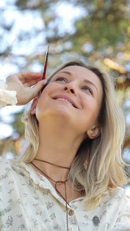 woman artist paints a picture in a summer park in sunlight hobby to paint pictures