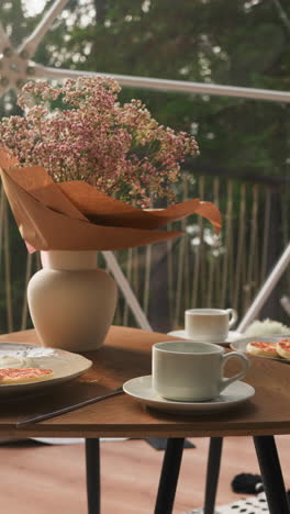 breakfast on glamping cottage glass terrace. low table paired with fluffy armchairs creates calm atmosphere to rest with stunning views. perfect morning