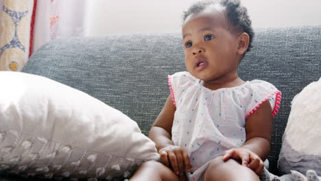 baby girl sitting on sofa and clapping at home