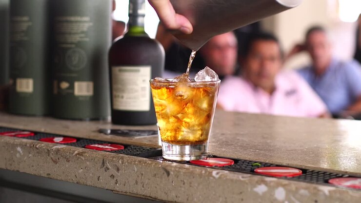 Ripresa al rallentatore di un cocktail alcolico che viene versato in un bicchiere con ghiaccio in un bar nei Caraibi.