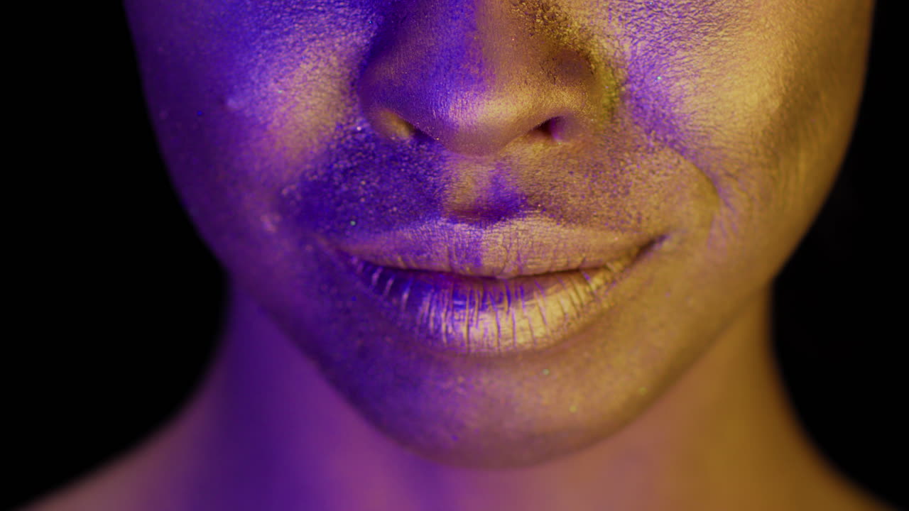 Close-up of woman's face with gold and purple makeup