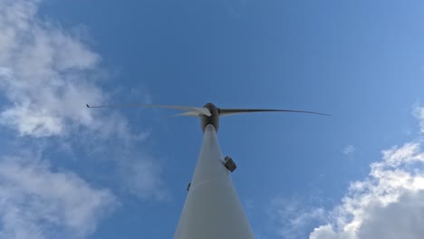 looking up and observing wind turbine in operation on sunny day