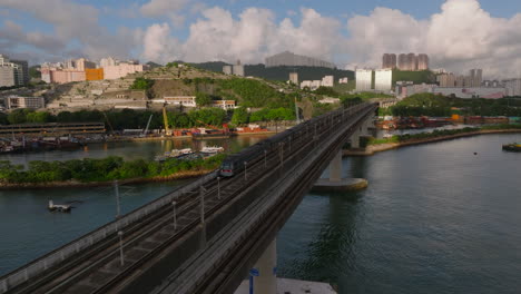 aerial tracking shot of mtr train from kwai chung to tsing yi during golden hour