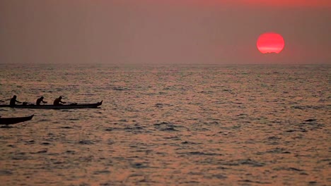 A-beautiful-shot-of-outrigger-canoes-passing-before-the-setting-sun-in-Hawaii