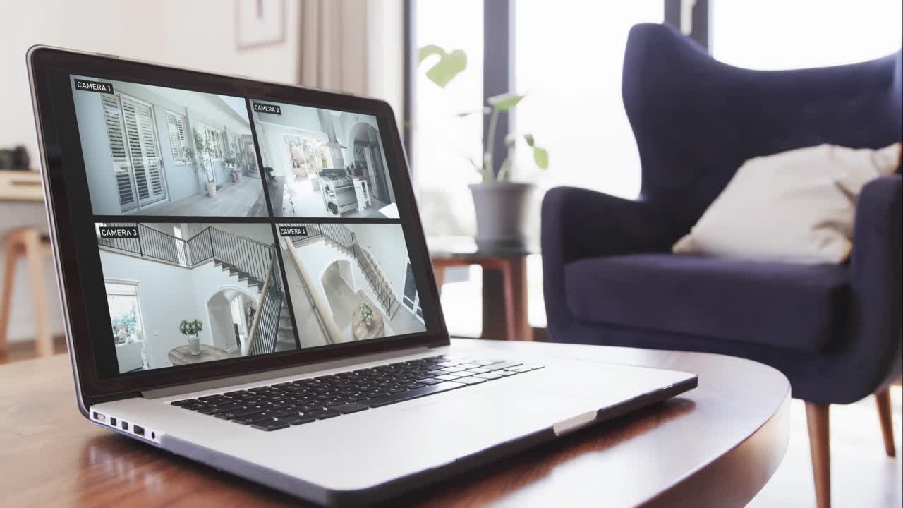 portátil en la mesa de café en la sala de estar con cámaras de seguridad en el hogar vistas en las pantallas, cámara lenta