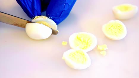 Close-up slow motion of a knife slicing a hard-boiled egg cleanly in half
