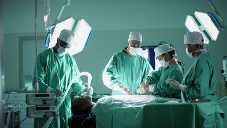 Diverse-male-and-female-surgeons-operating-on-patient-in-operating-theatre-at-hospital,-slow-motion