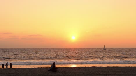 Couple-watching-the-sun-going-down-on-the-horizon-at-the-beach