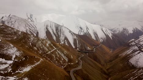 Brauner-Und-Weißer-Berg-Mit-Kalter,-Gefrorener-Eisstraße-Und-Schneebedeckten-Bergen-In-Wolken-Und-Nebel-Im-Hintergrund