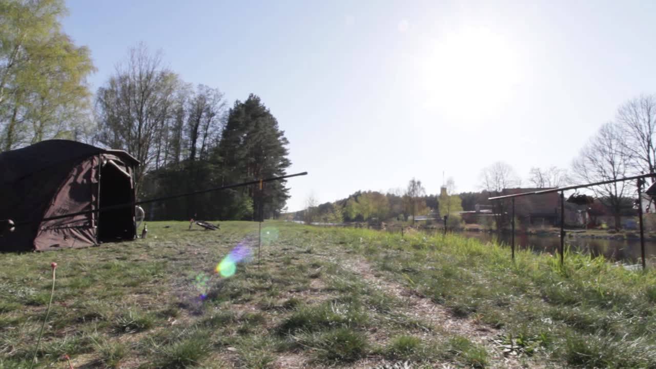 Fishing spot at the riverside with tent and fishing rods