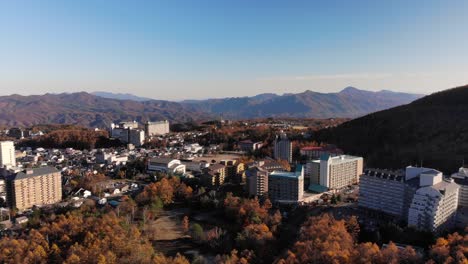 vista giratoria de drones sobre la ciudad de montaña en japón en un día azul brillante con colores otoñales