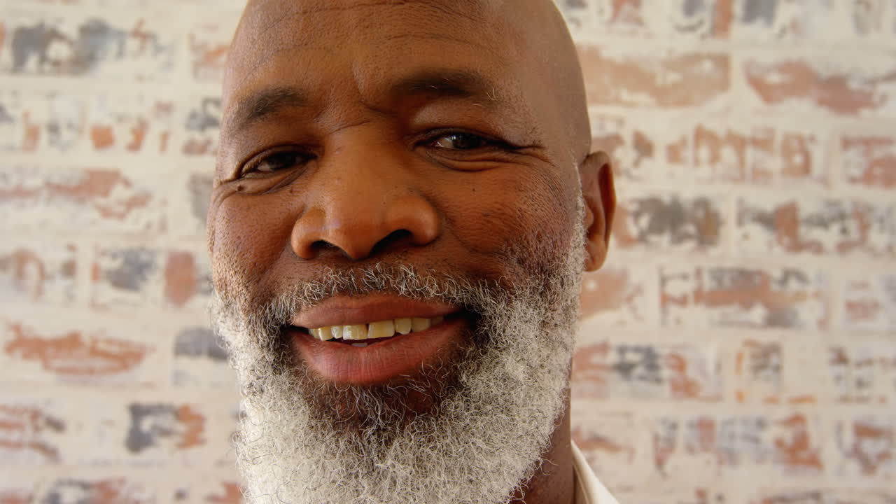 vista frontal de un hombre negro maduro mirando a la cámara en un cómodo hogar 4k