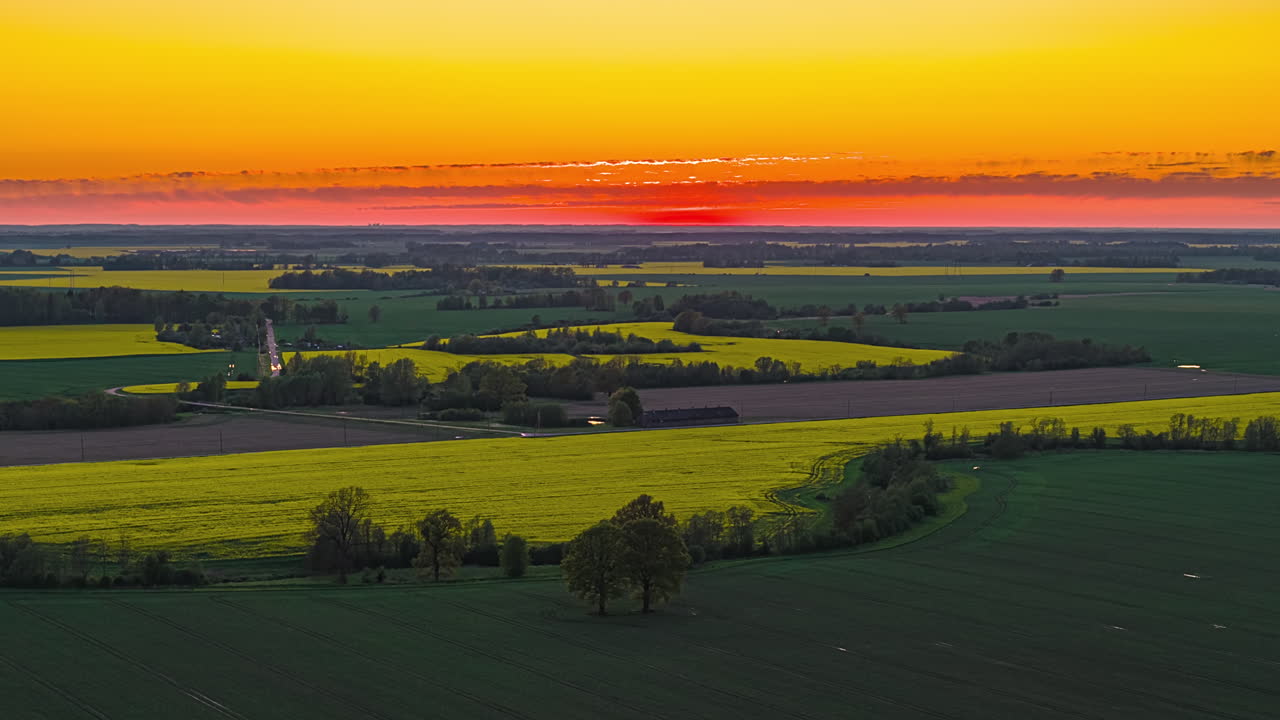 Sunset Casts a Golden Glow Over Blooming Canola Fields and Winding Country Roads Near Riga, Latvia - Timelapse