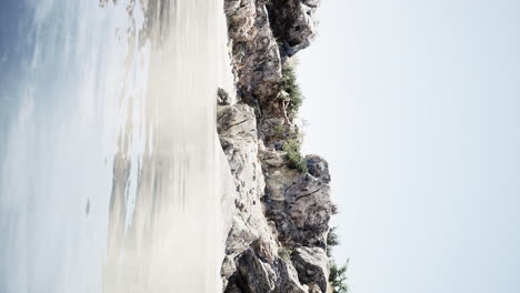 Video-Vertical-De-Una-Gran-Isla-Rocosa-En-Medio-Del-Agua-Del-Mar