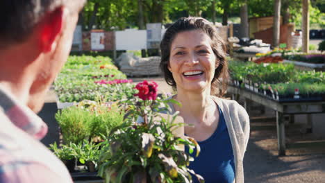 mature woman customer buying plant from male sales assistant in garden center