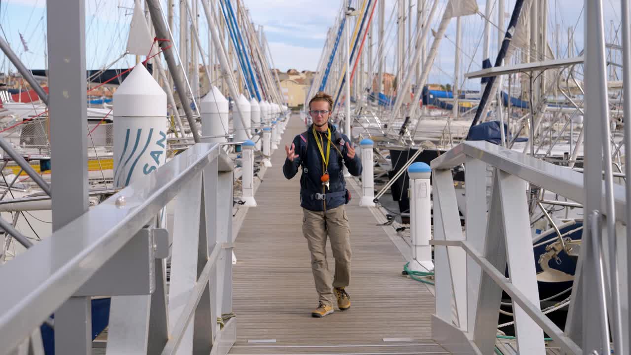 disparo en cámara lenta de un marinero hablando a la cámara mientras camina hacia su yate