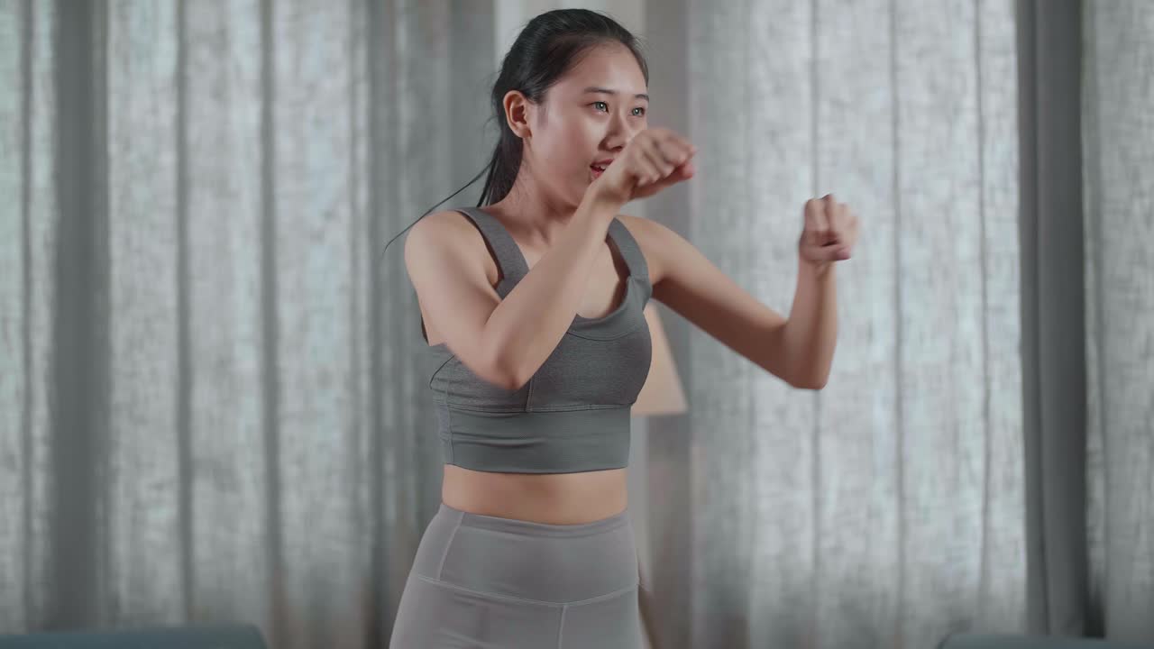 스포츠 옷을 입은 젊은 아시아 운동선수 여성의 근접 초상화가 집에서 매트에서 심장 근본 강화 운동을 하고 있습니다.
