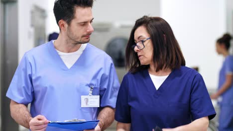 dos médicos discutiendo algunos registros médicos en el pasillo