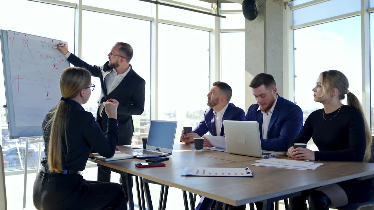 Business, technology and office concept - happy business team with laptop computers, documents and coffee. Meeting before the start of the working day to discuss a business plan