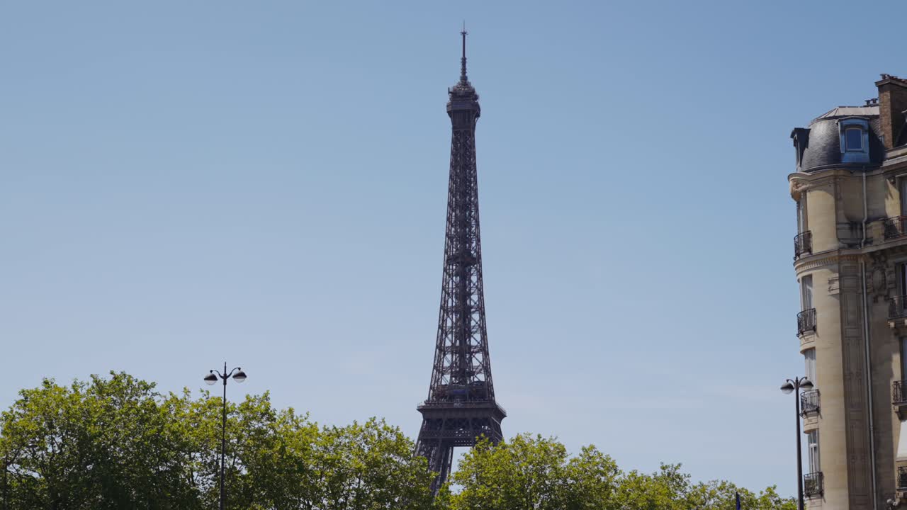The Eiffel Tower visible above trees and a building in Paris