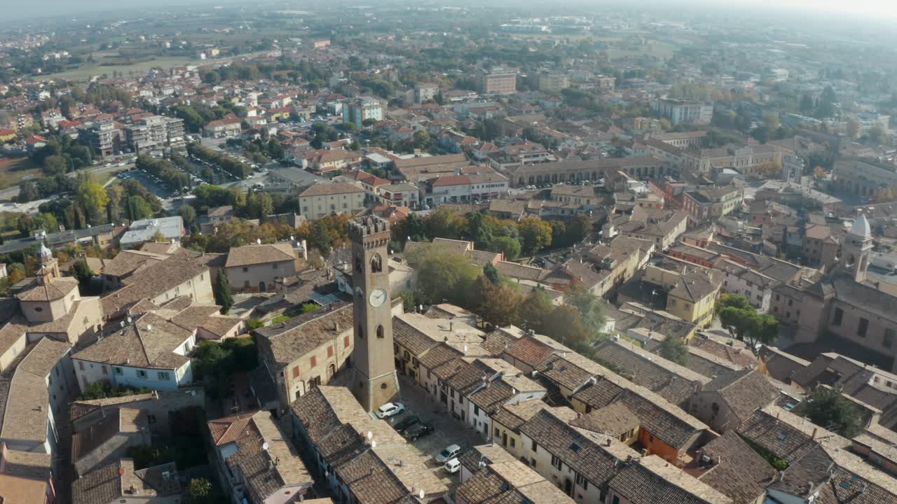 Ripresa aerea con drone di una torre dell'orologio medievale e degli edifici circostanti con tetti in tegole a Santarcangelo di Romagna
