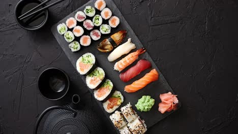 assortment of different kinds of sushi rolls placed on black stone board