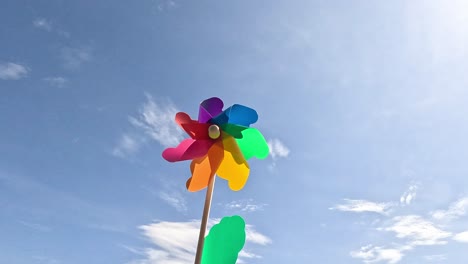 multicolored pinwheel rotates against a blue sky.