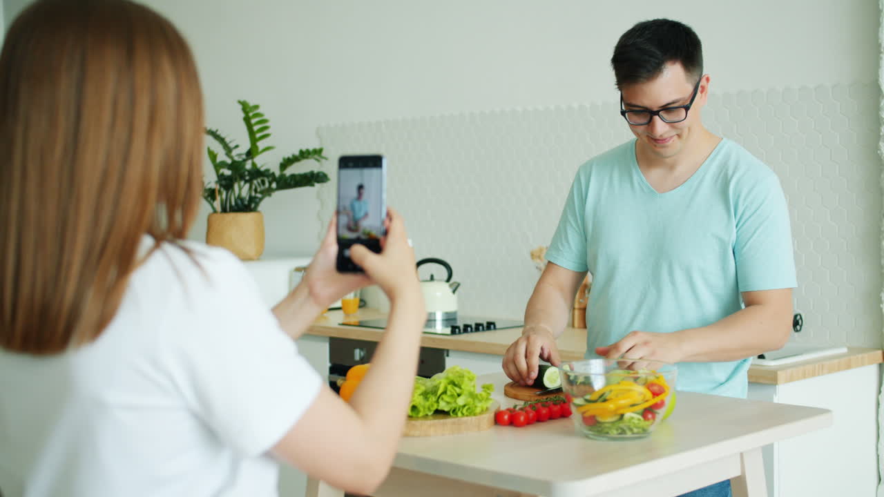 Couple cooking together and taking a video of the food