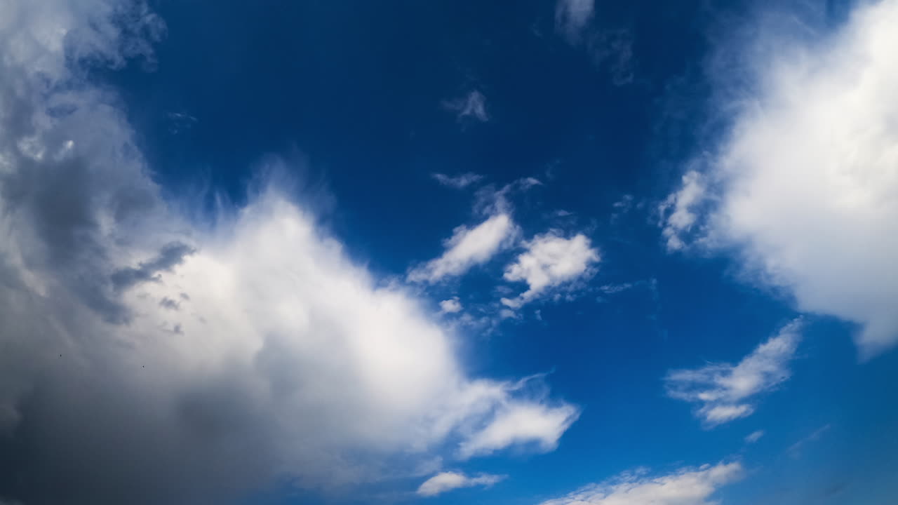 Deep blue sky with fluffy soft clouds. Soft white clouds transform in the atmosphere. Low angle view. Timelapse.
