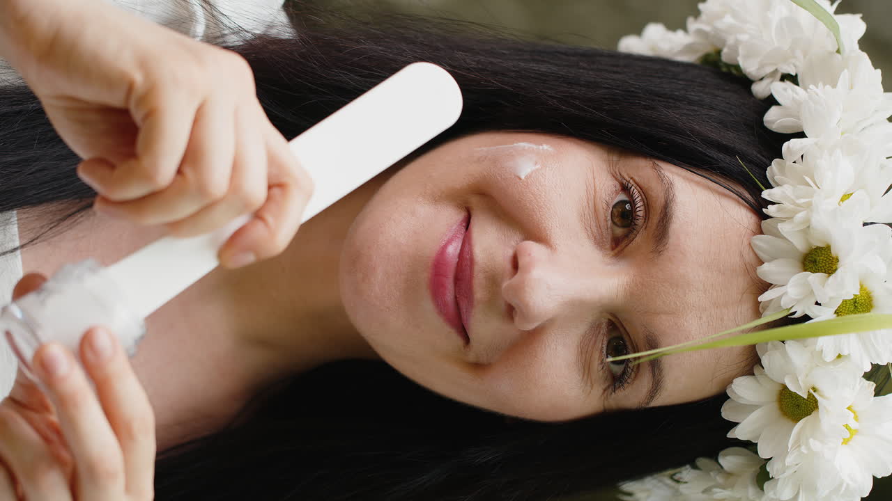 feliz 40 años de edad madura mujer de mediana edad aplicando la piel facial crema hidratante tratamiento de belleza