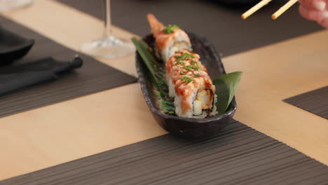 eating shrimp tempura sushi rolls with chopsticks in a japanese restaurant - close up