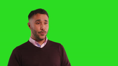 Close-Up-Studio-Portrait-Of-Mature-Male-Teacher-Talking-To-Class-Standing-Against-Green-Screen-Background