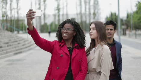 two women and man making selfie outside, posing, smiling