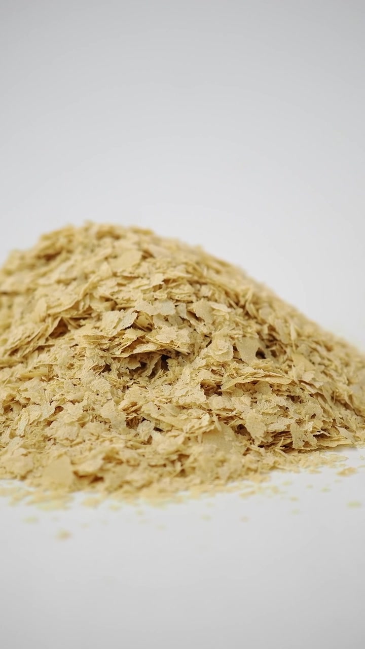 Pila di fiocchi di lievito alimentare su sfondo bianco