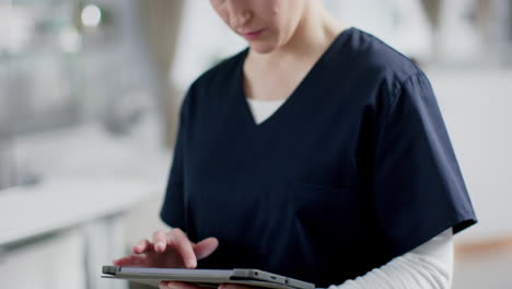 Retrato-De-Una-Feliz-Doctora-Caucásica-Usando-Batas-Usando-Una-Tableta-En-El-Hospital,-Cámara-Lenta