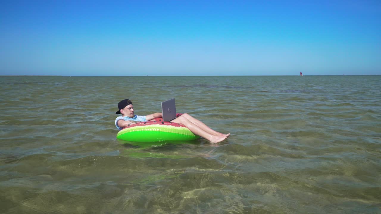 A young business person is enthusiastically working behind a laptop swaying on the waves of sea