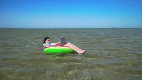 a young business person is enthusiastically working behind a laptop swaying on the waves of sea